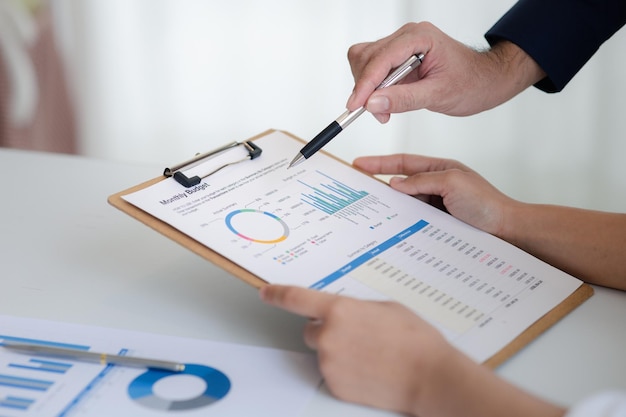 Company meeting room has businessmen and finance managers meeting together on finance topics they are looking at information on documents and discussing together Concept company financial management