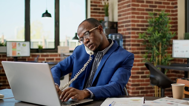 Company secretary using landline phone to have remote conversation with clients and colleagues at startup job. Answering office telephone to discuss with people on phone line.