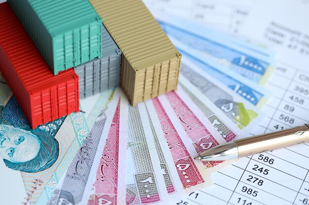 Company shipping cargo containers in Iran with rials money bills and pen