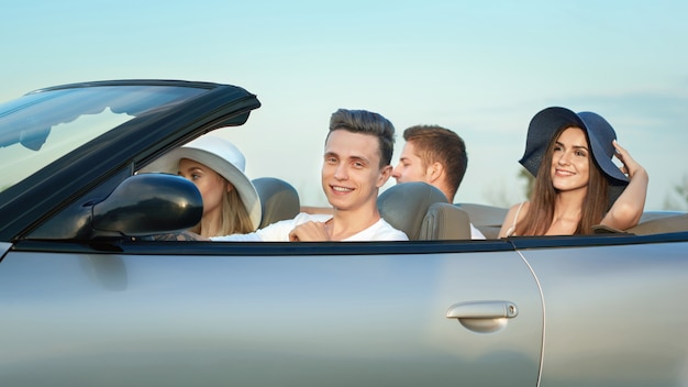 Company sitting in cabriolet, traveling by car.