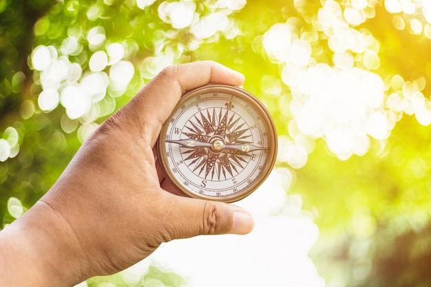 Photo compass on hand and green bokeh with sunlight.