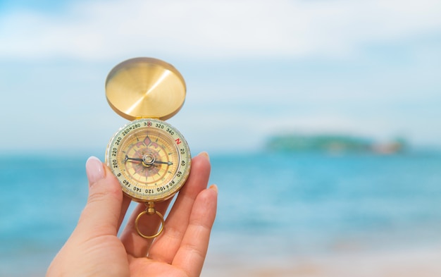 Compass on hand in the sea and the beach.