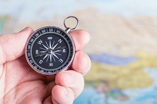 Compass in hand over travel map