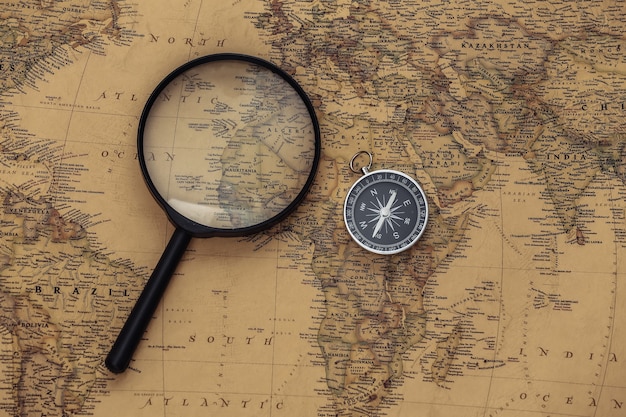 Compass and magnifying glass on old map. Travel, adventure concept