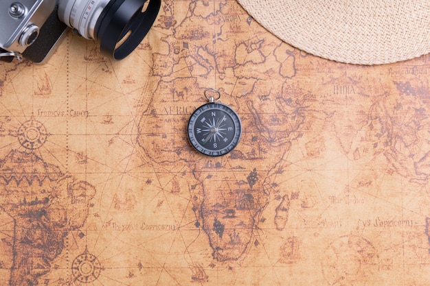 Bussola sulla mappa con fotocamera vintage e cappello per il viaggiatore