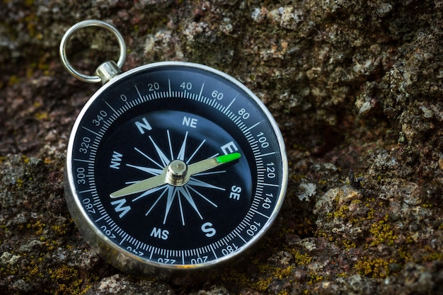 Compass placed on the rock in forest. Closeup and copy space. Concept of jungle adventure travel.