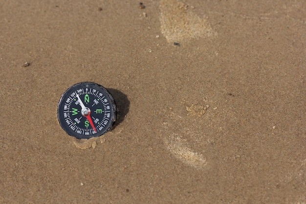 Bussola che punta a sud-ovest posa sulla spiaggia di sabbia