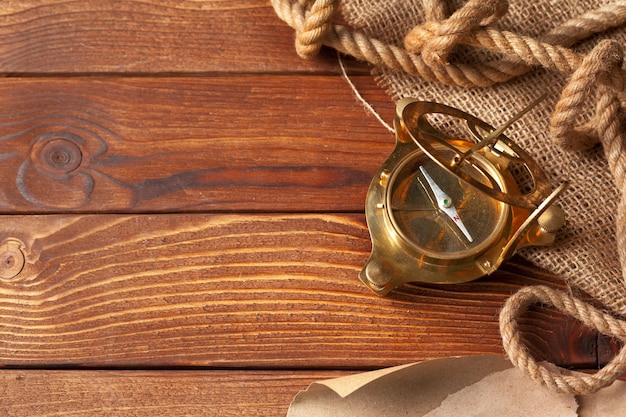 Compass and rope on old wooden boards