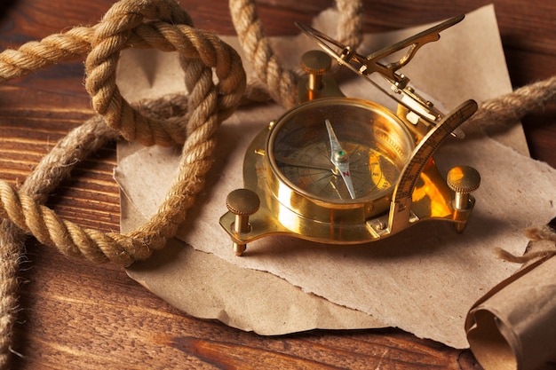 Compass and rope on wooden table, close up