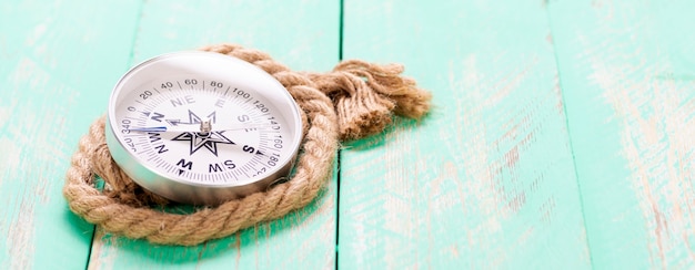 Compass and rope on wooden texture background.