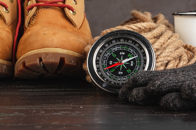 Compass surrounded by mountain gear tools on wooden background