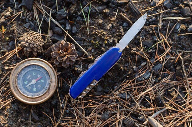 Compass and survival knife on background of earthClose up