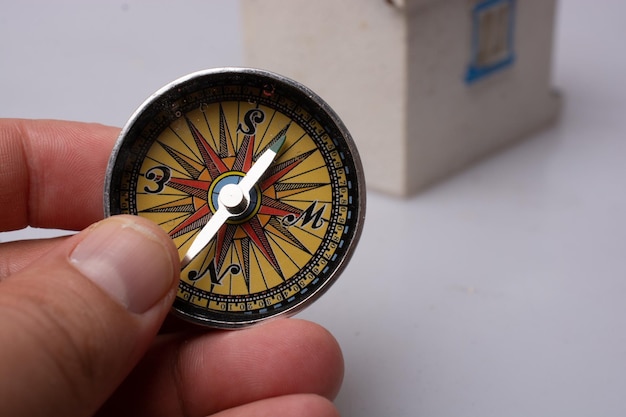 Compass tool in hand before a model house