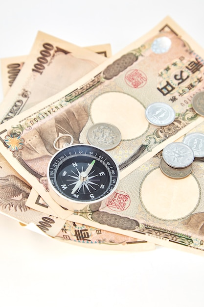 白い背景に日本の円の紙幣と円のコインとコンパス