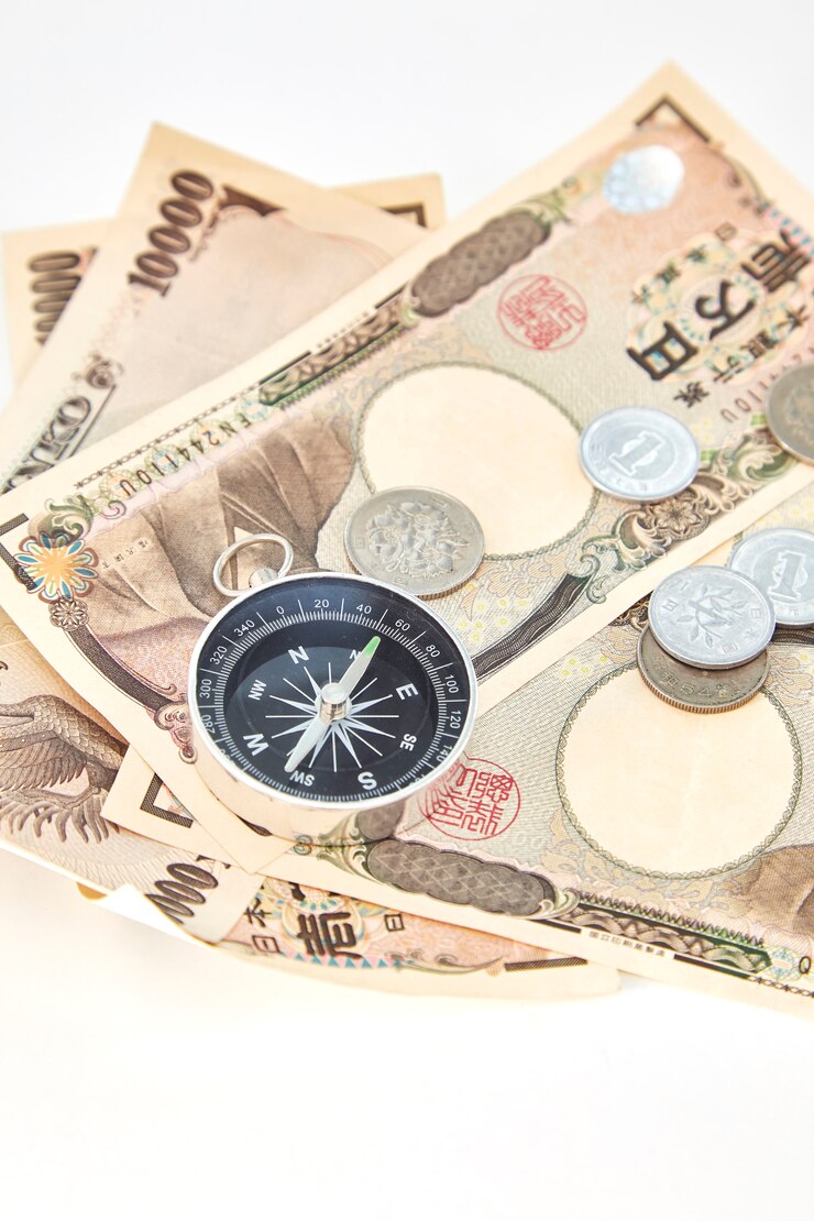 白い背景に日本の円の紙幣と円のコインとコンパス