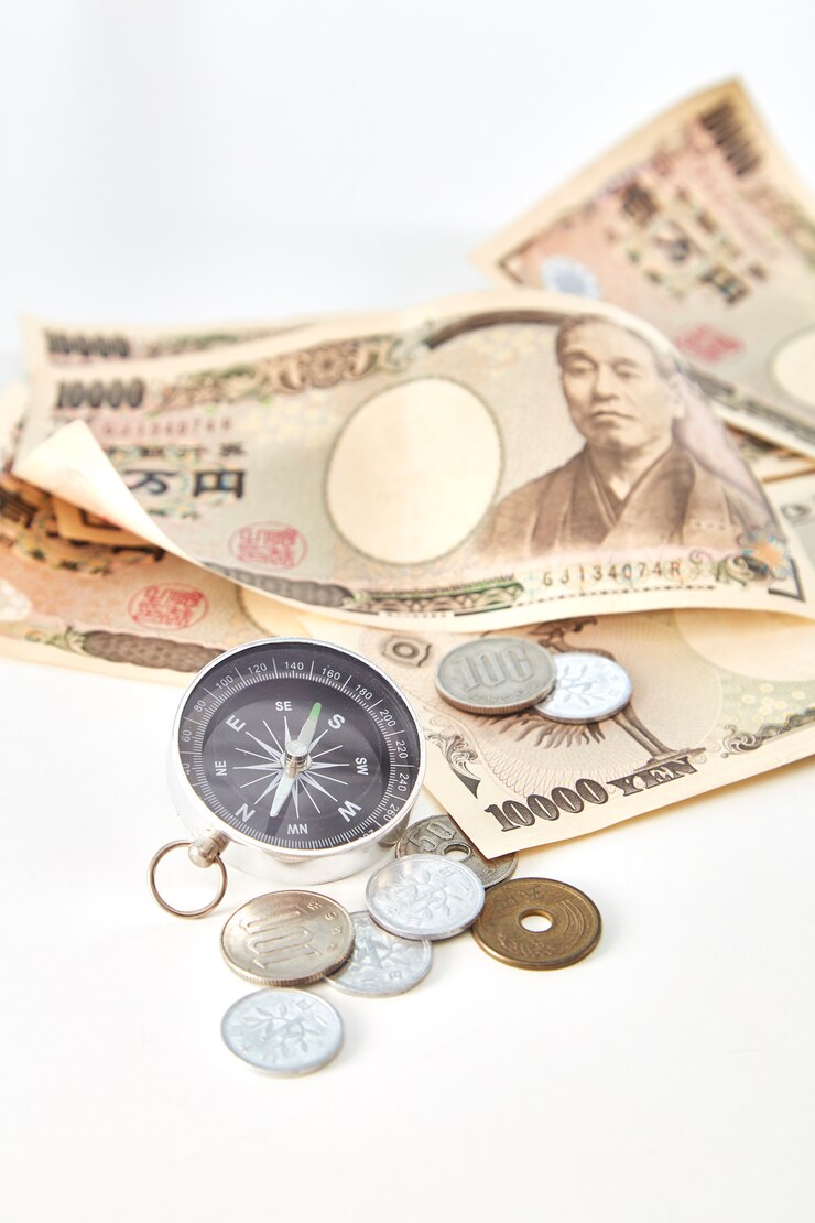 白い背景に日本の円の紙幣と円のコインとコンパス