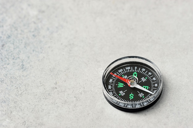 Compass with a red magnetic arrow on a gray background with space for text