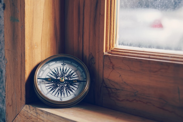 Bussola sulla finestra in legno per il viaggio e il concetto di navigazione