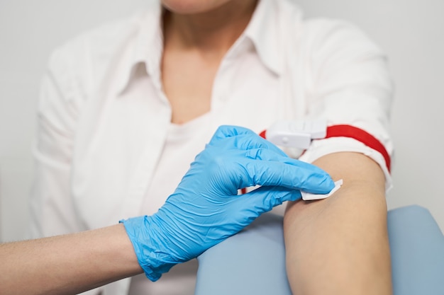 Competent medical worker wearing rubber gloves while disinfecting hand before doing prick