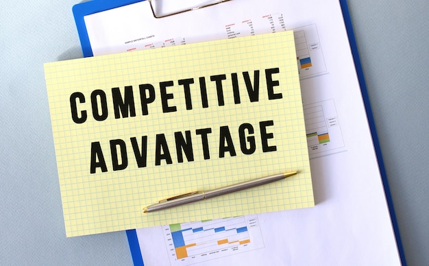 COMPETITIVE ADVANTAGE text written on notepad with pencil. Notepad on a folder with diagrams. Financial concept.