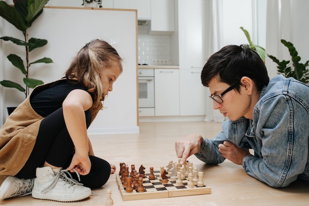 Competitive chess match between dad and his child daughter both\
excited and having fun side view on the kitchen floor