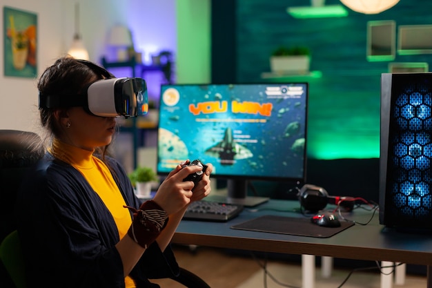 Photo competitive gamer looking into powerful computer playing online shooter game late at night with vr headset and console wireless. virtual online streaming cyber performing during game tournament