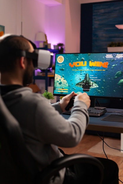 Competitive gamer using professional joystick playing online\
shooter game late at night with vr headset. virtual online\
streaming cyber performing during live game tournament