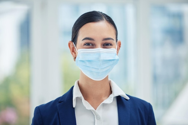 Compliance face medical mask and covid rules at work with a business woman in corporate office Portrait of a female worker practice social distancing at workplace regulations and hygiene