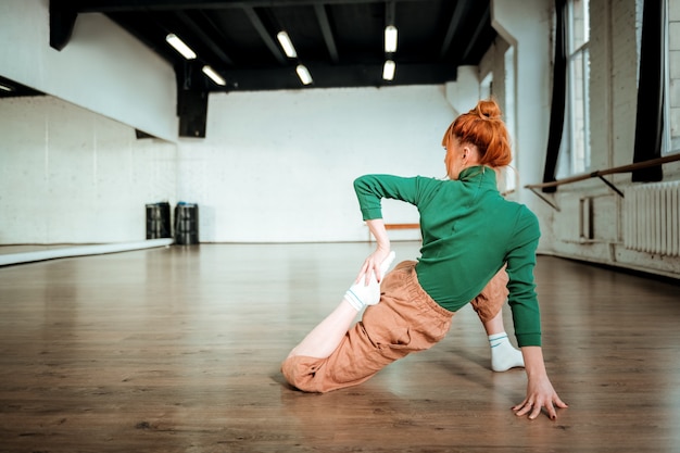 complicated asana. professional yoga coach wearing a green turtleneck doing complicated asana