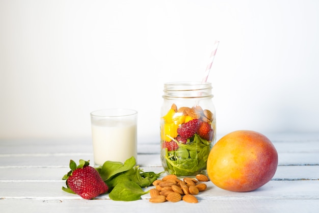 Photo components of healthy green reach vitamins smoothie with baby leaf spinach, mango, almond milk and strawberry