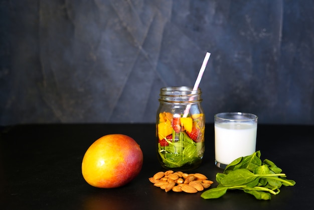 아기 잎 시금치, 망고, 아몬드 우유 및 딸기가 들어간 건강한 녹색 도달 비타민 스무디의 구성 요소