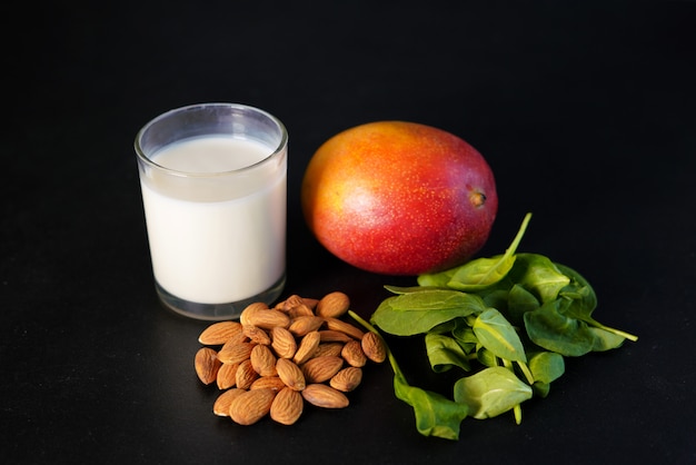 Components of healthy Green Reach Vitamins Smoothie with baby leaf spinach, mango, almond milk and strawberry