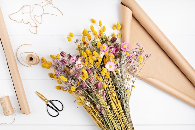 Composing bouquet of dry flowers and herbs, trendy interior decoration, artisan florist shop idea. Top view, flat lay