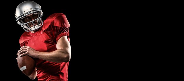 Composite image of american football player in red jersey looking away while holding ball