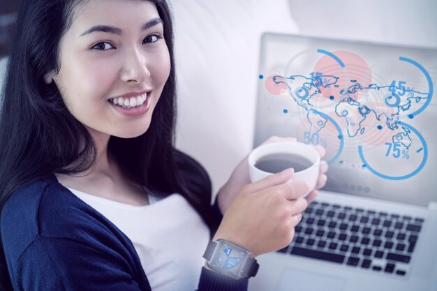 Составное изображение азиатки, отдыхающей на диване с кофе с помощью ноутбука