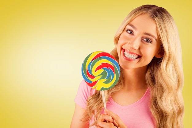 Composite image of a beautiful woman holding a giant lollipop