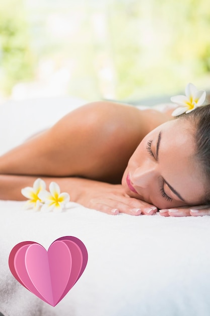 Composite image of beautiful woman lying on massage table at spa center