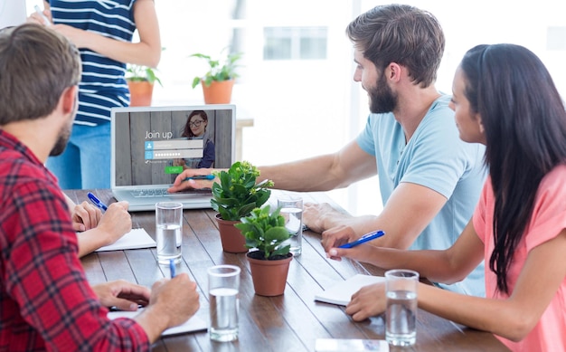 Composite image of business team using a laptop