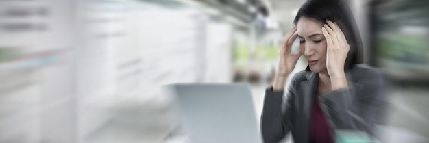 Composite image of businesswoman with laptop suffering from headache