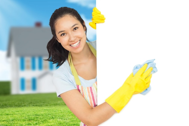 Composite image of cheerful woman cleaning white surface