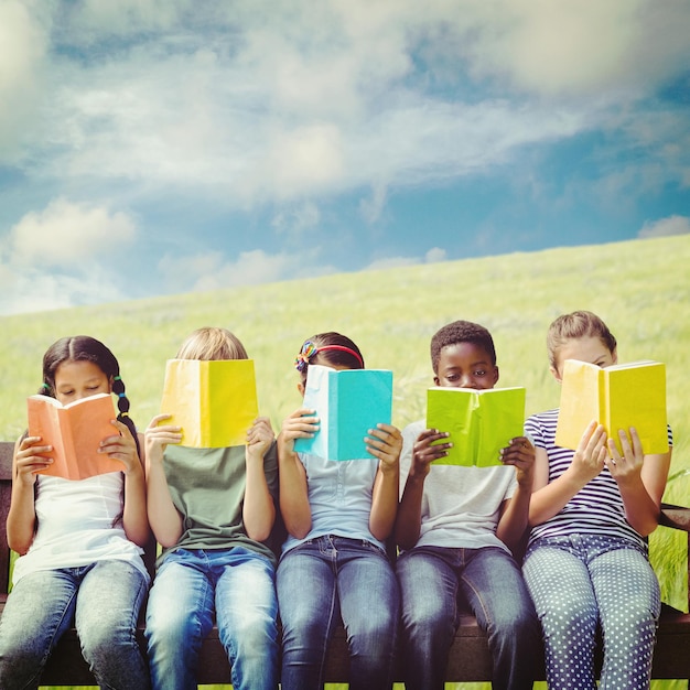 Foto immagine composita di bambini che leggono libri al parco