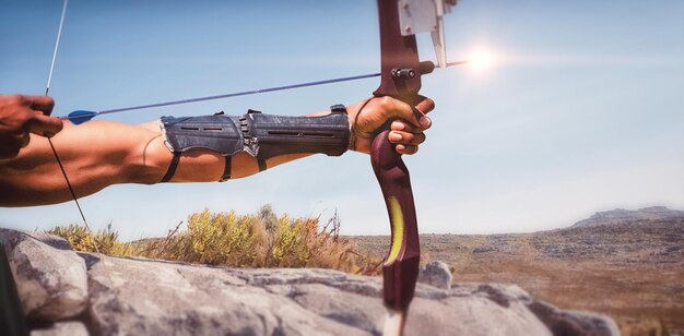 Composite image of close up of man stretching his bow