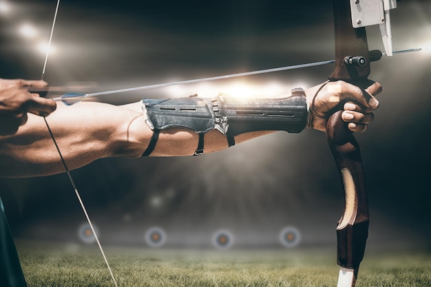 Composite image of close up of man stretching his bow