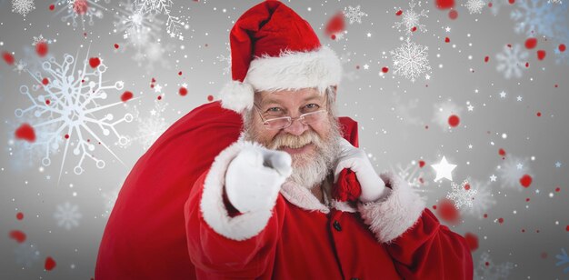 Composite image of closeup portrait of santa claus pointing while carrying christmas bag