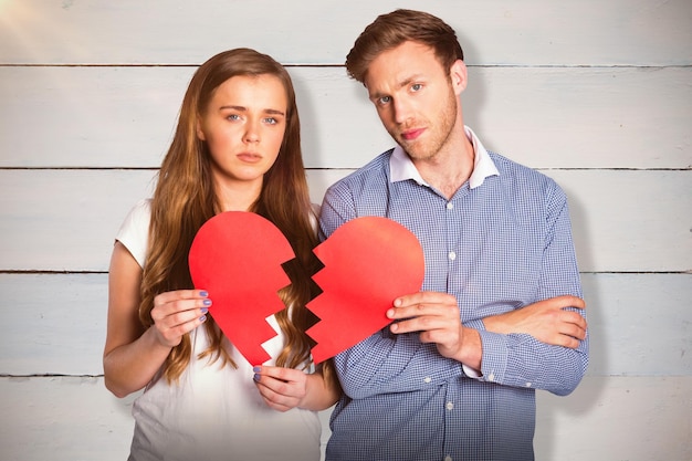 Composite image of couple holding broken heart