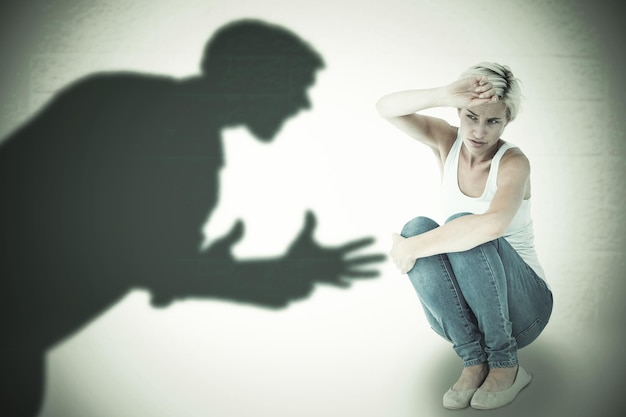composite image of crouching sad woman holding her hand