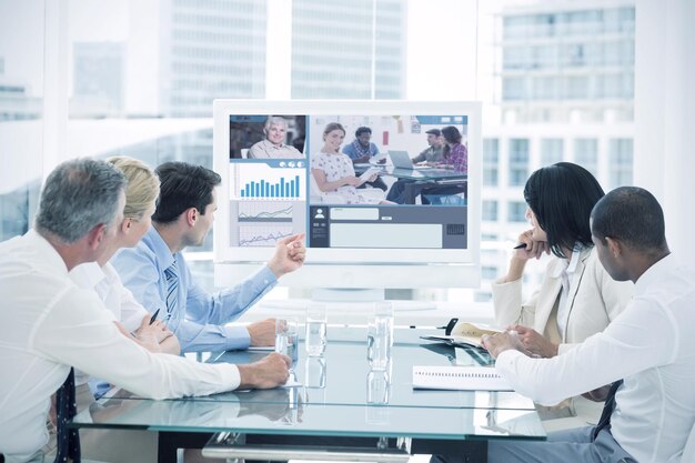 Composite image of editor holding tablet and smiling as team works behind her