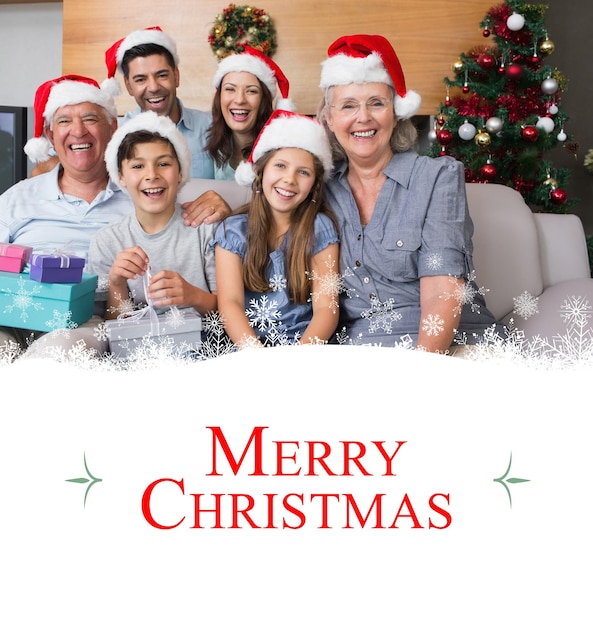 Composite image of extended family in christmas hats with gift boxes in living room