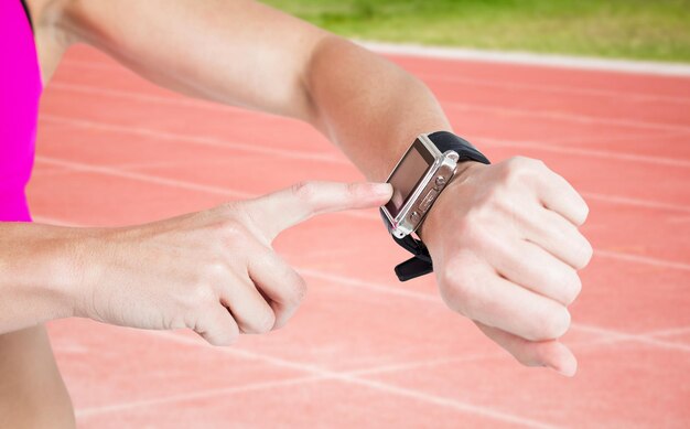 Composite image of female athlete using her smart watch