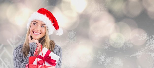 Composite image of festive blonde holding christmas gift and bag